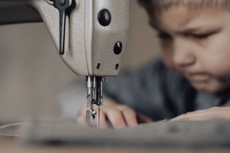 Close-up of a focused child using a sewing machine, emphasizing creativity and craftsmanship.